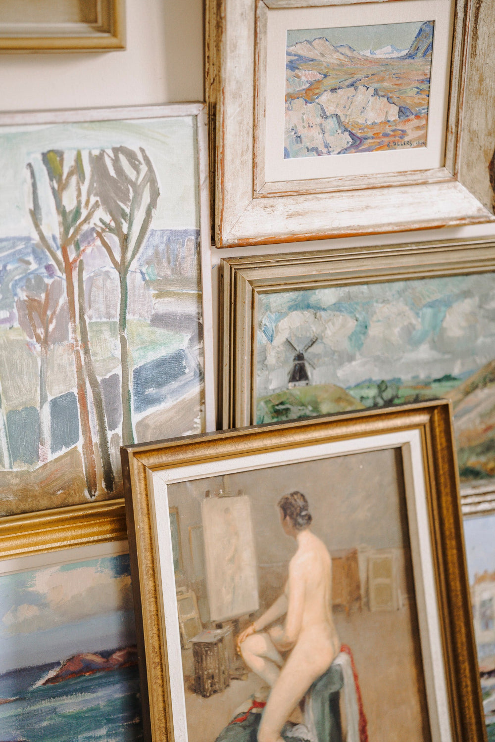 Collection of framed vintage oil paintings and artwork, including mid-century french landscapes and a nude figure. Curated by Hue + Holasz.