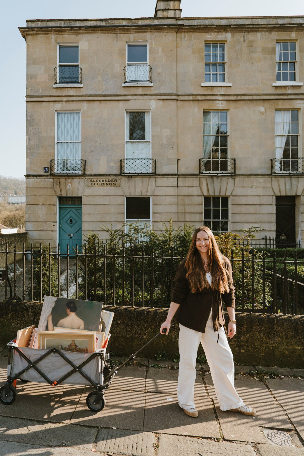 Woman sourcing original vintage art and vintage oil paintings with a cart of collected artworks.