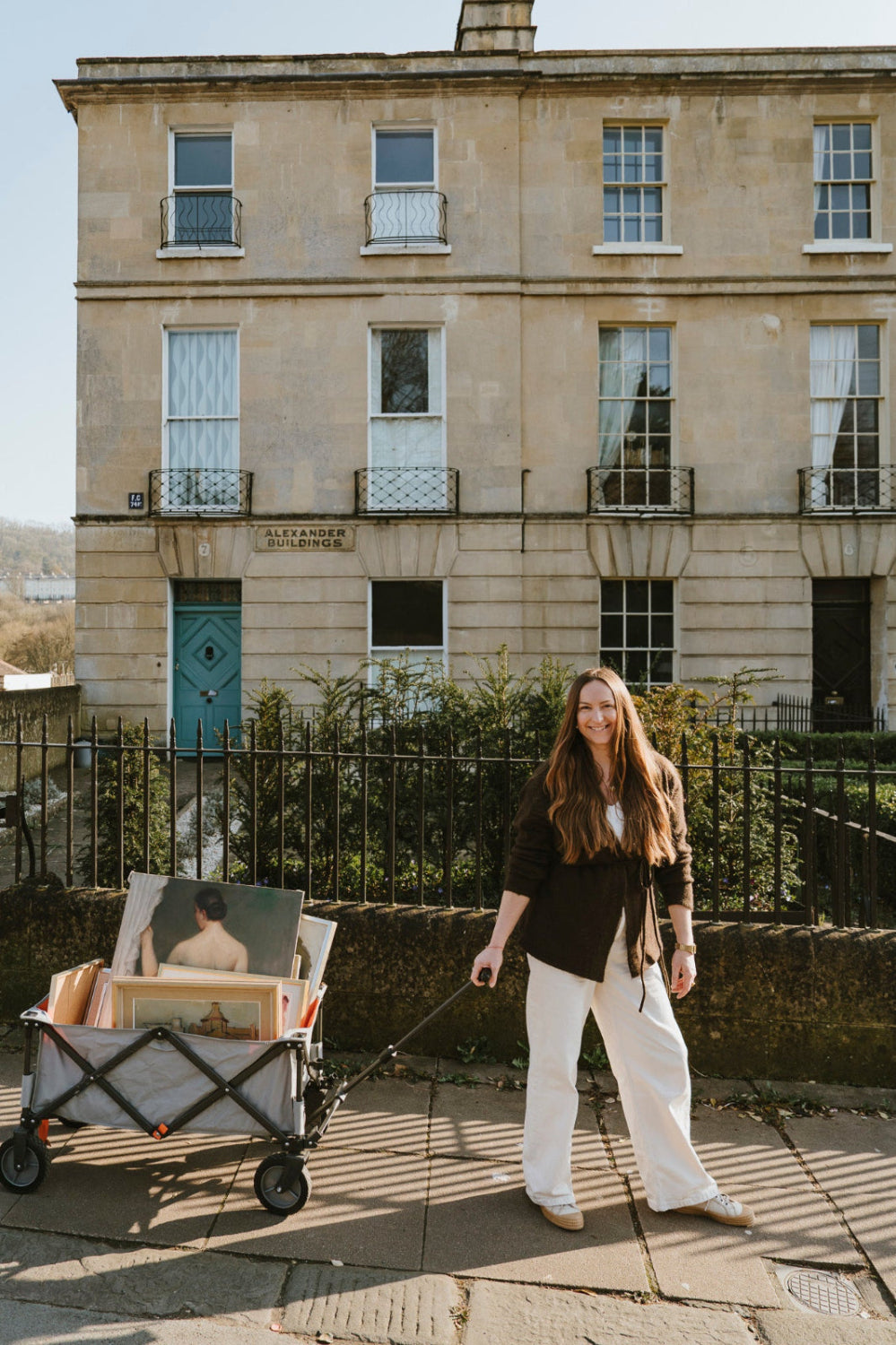 Woman sourcing original vintage art and vintage oil paintings with a cart of collected artworks.