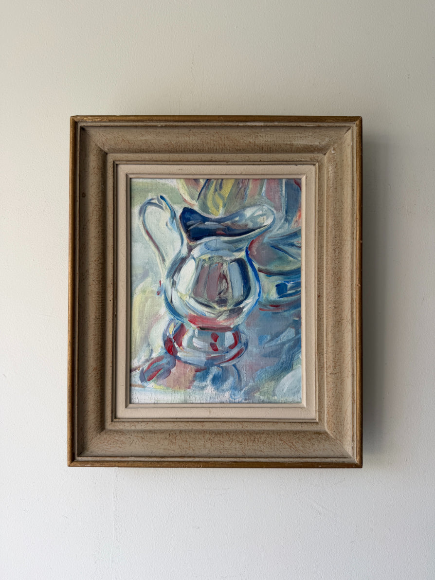 A framed vintage still life oil painting of a glass pitcher, featuring blue, white, and red brushstrokes, housed in a rustic brown wooden frame. Available at Hue. 