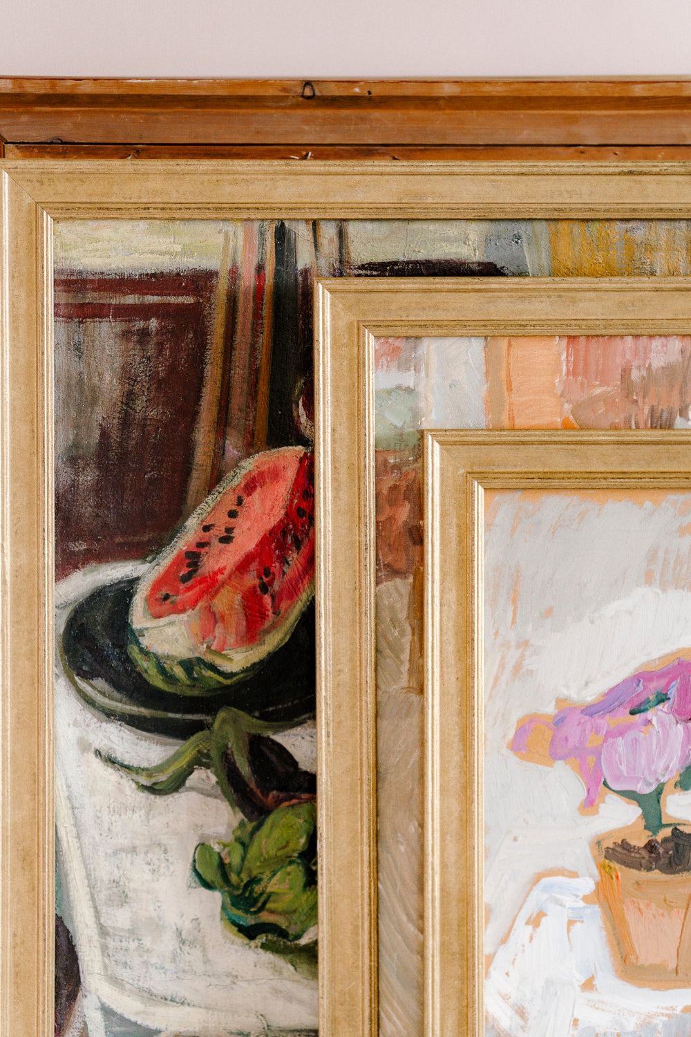 Layered original vintage still life paintings in gilt frames, featuring watermelon and floral subjects from the Hue + Holasz art collection.